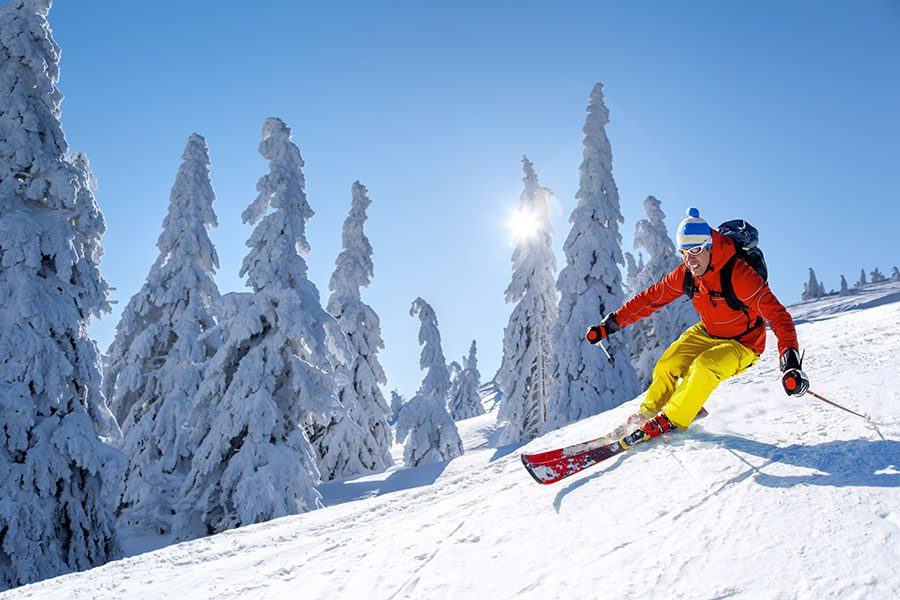 Travel Insurance - View of Man Skiing Down Snowy Mountain in the Alps
