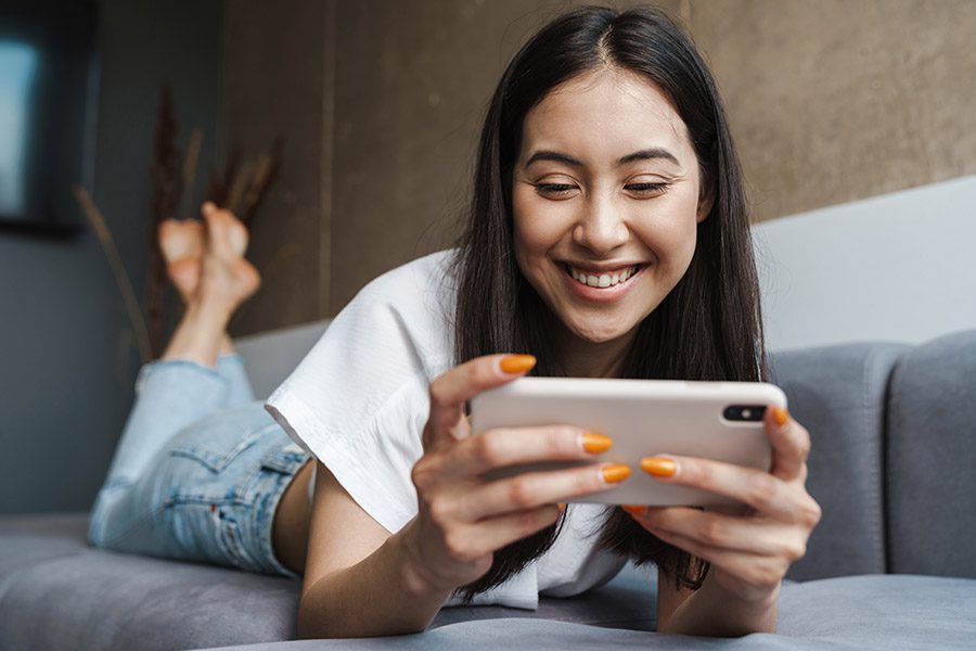 Video Library - Young Woman at Home Watching Videos by Mobile Phone