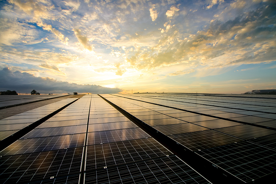 Solar - View of Rows of Solar Panels on an Open Field with a Dramatic Sunset Sky in Renewable Energy Concept