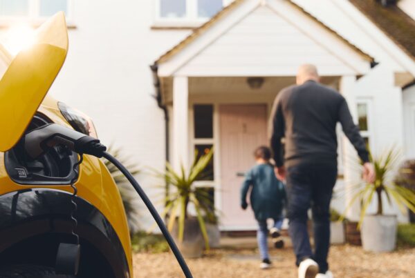 Electric car plugged in while family walks into their home